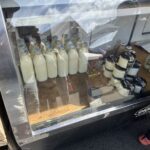 A display of milk bottles and jars are arranged in a case.
