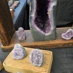 A display of purple rocks and crystals, including a large purple crystal and smaller purple rocks.