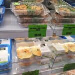 A display of various food items, including a salmon cake, is available for purchase.
