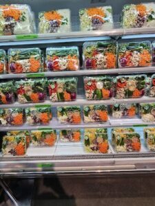 A display of various salads in plastic containers.