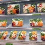 A display of various vegetable salads in plastic containers.