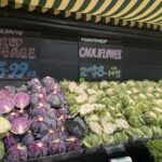 A display of vegetables at a market, including cabbage and cauliflower.