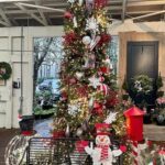 A festive Christmas tree with a bench underneath it, decorated with a snowman and a red and white striped hat.