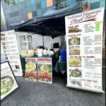A food stand with a menu and a tent.