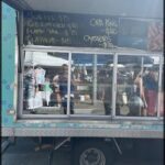 A food truck with a menu board displaying prices for various items.