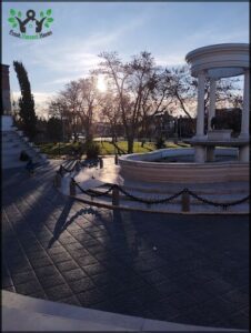 A fountain in a park with a sunset in the background.