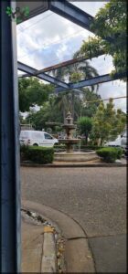 A fountain with a van parked nearby.