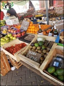 A fruit stand with a variety of fruits and vegetables, including apples, oranges, and avocados.