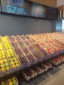 A fruit stand with a variety of fruits, including apples, oranges, and plums.
