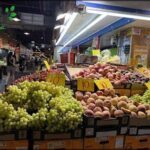 A fruit stand with a variety of fruits, including grapes, apples, and peaches.