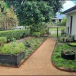 A garden pathway leads to a fence with a gate.