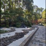 A garden with a stone pathway and a red gate.