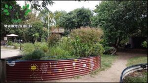 A garden with a variety of plants, including a large flower pot with a sunflower painted on it.