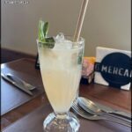 A glass of a minty drink sits on a table, accompanied by a fork and knife.