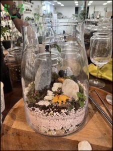 A glass vase filled with rocks and a tree inside.