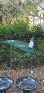 A gnome is sitting on a sign that reads "Kids Parking."