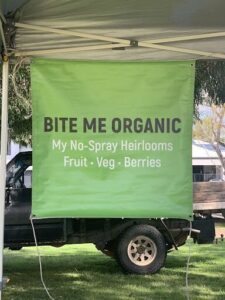 A green sign that says "Bite Me Organic" is hanging from a truck.