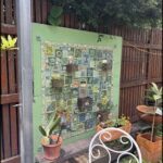 A green wall with a variety of plants and a bench in front of it.