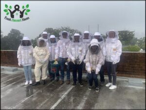 A group of beekeepers wearing white suits pose for a photo.