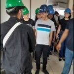 A group of construction workers wearing hard hats and safety gear are gathered together, possibly discussing their work or taking a break.