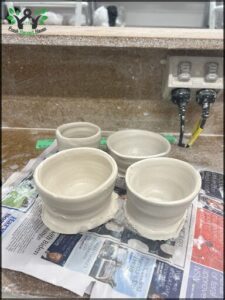 A group of four white bowls are sitting on a newspaper.