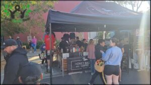 A group of people are gathered around a coffee stand, with some of them holding baskets.