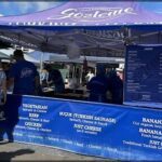A group of people are gathered around a food stand, enjoying a variety of dishes.