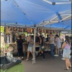 A group of people are gathered around a food truck, ordering and enjoying their meals.
