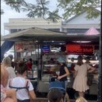 A group of people are gathered around a food truck, waiting to be served.