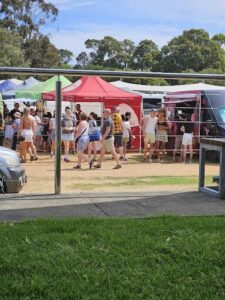 A group of people are gathered around a red tent, possibly at a festival or event.