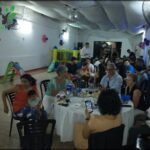 A group of people are gathered around a table, enjoying a meal and each other's company.