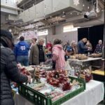 A group of people are gathered around a table filled with Christmas presents.