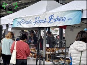 A group of people are gathered around a table filled with French pastries.