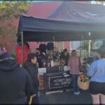 A group of people are gathered around a table with a tent covering it, likely at a coffee shop.