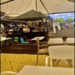 A group of people are gathered around a table with a tent in the background.