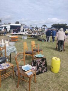 A group of people are gathered in a field, surrounded by tables and chairs.