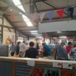 A group of people are gathered in a market, shopping and socializing.