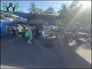 A group of people are gathered in a parking lot, enjoying a meal together.