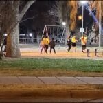 A group of people are playing a game of basketball on a court at night.