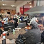 A group of people are sitting at a counter in a restaurant, enjoying their meal.