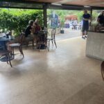A group of people are sitting at tables outside a restaurant, enjoying their time together.