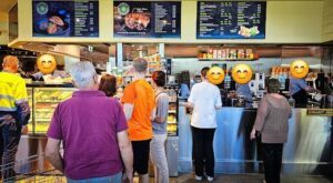 A group of people are standing in line at a cafe, waiting to order their food.