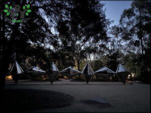 A group of silver sculptures are displayed in a park.