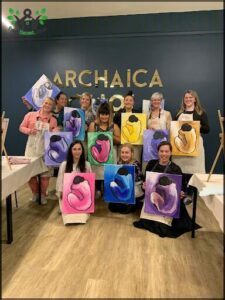 A group of women pose with their artwork, which includes paintings of naked figures.
