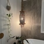 A hanging light fixture with a wicker design hangs above a bathroom sink.