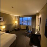 A hotel room with a desk, chair, and bed.