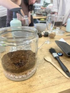 A jar of dirt sits on a table with other items.