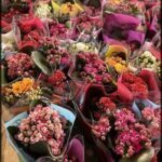 A large assortment of colorful flowers in a variety of bags.