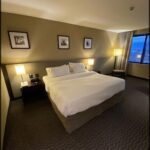 A large bed with a white comforter and brown headboard.