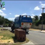 A large blue truck is parked in front of a brick mailbox, possibly for a pickup or delivery.